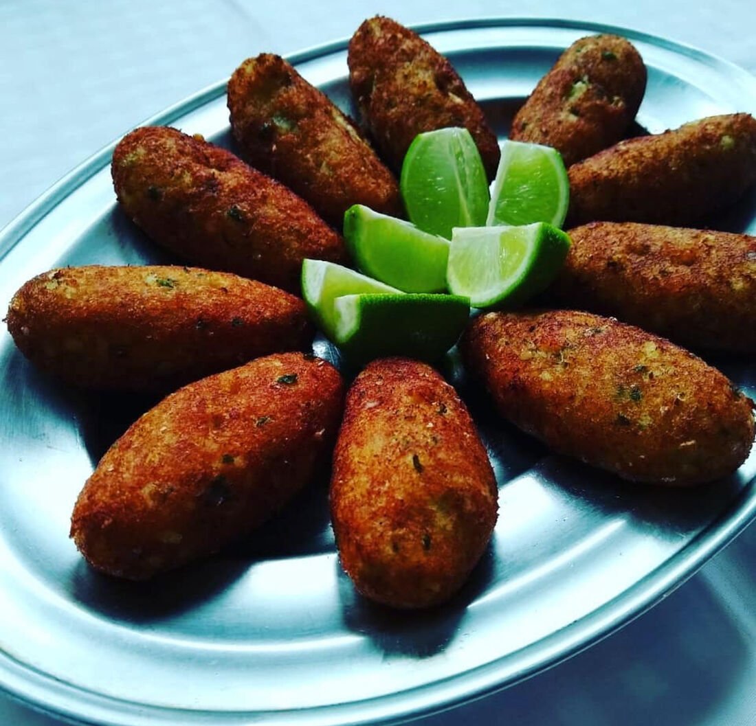 Porção de bolinhos de bacalhau com limão