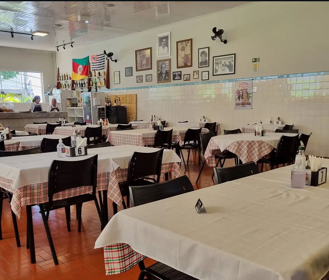 Salão do Restaurante Pipo com mesas postas e parede de fotos antigas que contam a história da casa